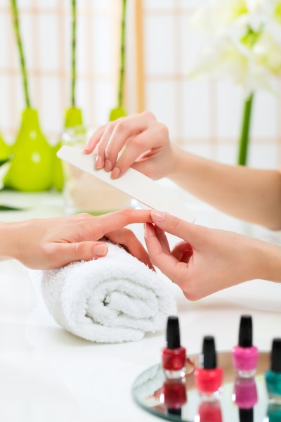 Woman in a nail salon receiving a manicure by a beautician